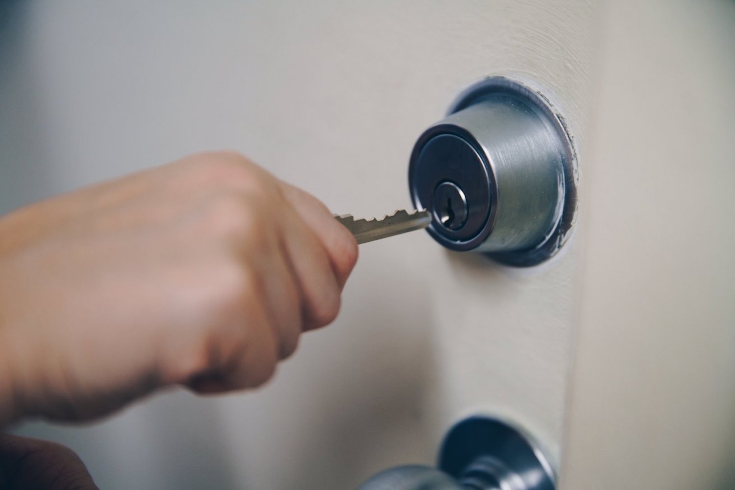 A person using a key in a door